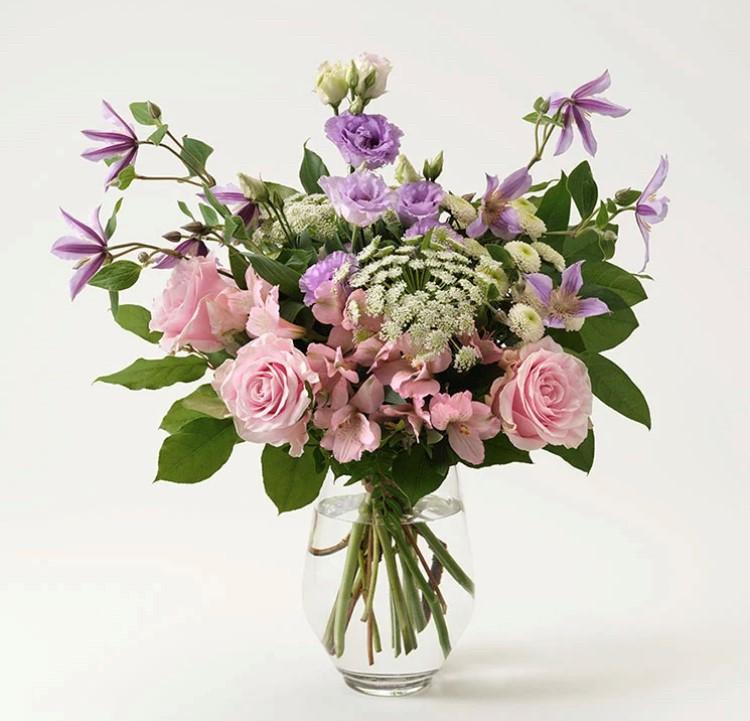 Interfloras junibukett, med rosa rosor, lila clematis, prärieklockor och grönt. Beställ blommorna i Interfloras egen e-butik!